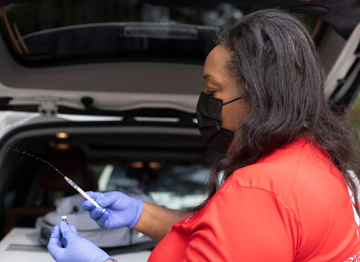 Dr. Nerissa Price prepares a syringe of COVID-19 vaccine from the back of her car as she make a house-call in a southeast Raleigh neighborhood on Friday, October 8, 2021 in Raleigh, N.C.