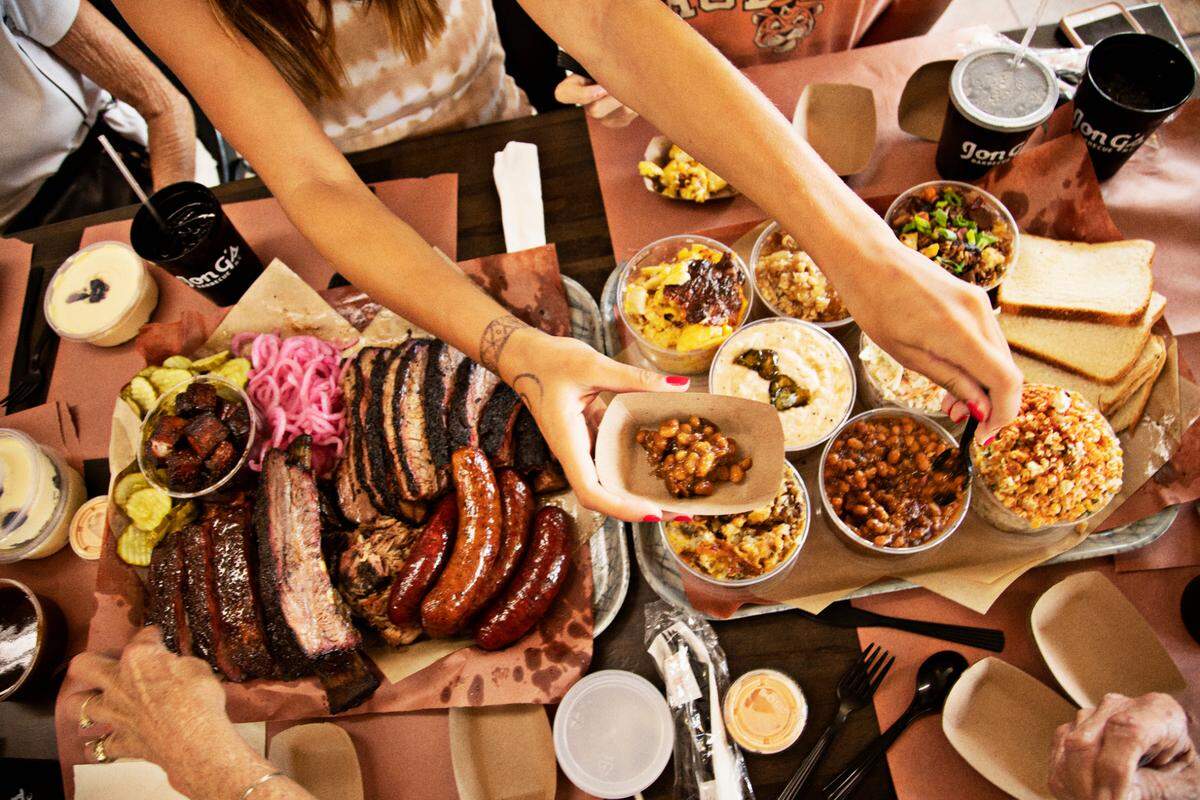 Kelly Kirkman’s family digs into an order that includes ribs, brisket, pulled pork, turkey and house-made sausage links along with a variety of sides including mac & cheese, brown sugar smoked beans, jalapeño cheese grits, cole slaw, and Mexican street corn salad at Jon G’s Barbecue on Saturday, June 22, 2022, in Peachland, NC.