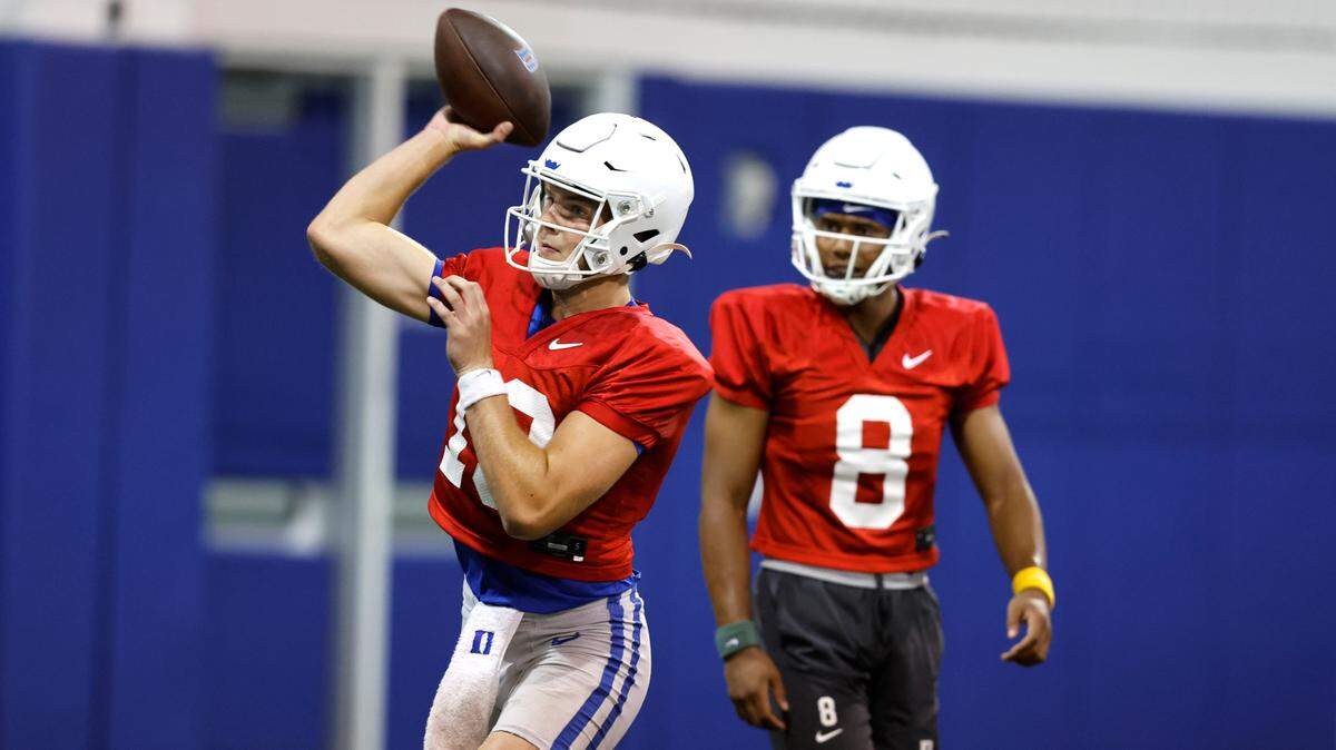 Duke quarterback Riley Leonard (13) passes as quarterback Jordan Moore (8) gets ready to run the drill during the Blue Devils’ first practice of fall camp in Durham. N.C. Tuesday, August 2, 2022.