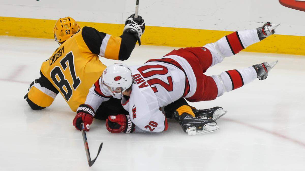 Pittsburgh Penguins’ Sidney Crosby (87) and Carolina Hurricanes’ Sebastian Aho (20) slide across the ice after colliding during the first period of an NHL hockey game, Sunday, March 8, 2020, in Pittsburgh. (AP Photo/Keith Srakocic)