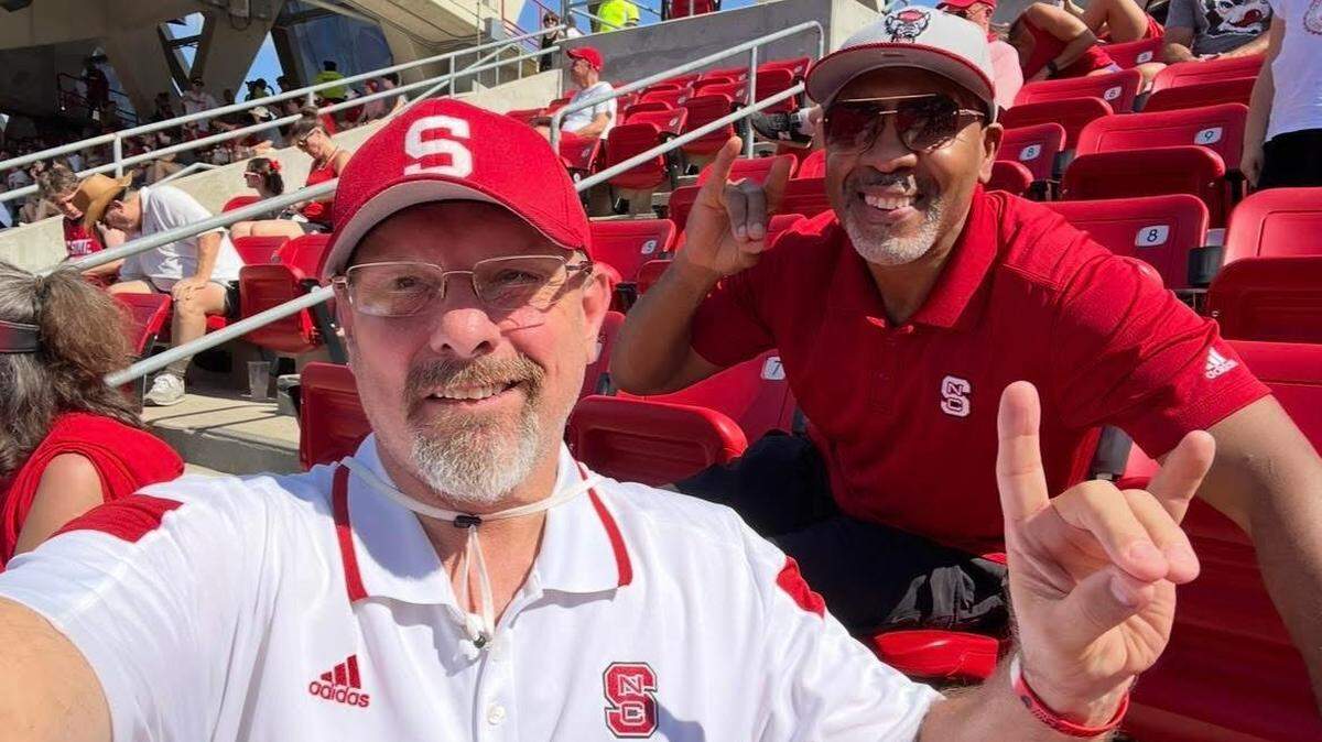 N.C. State alumnus and athletics supporter Chuck Coates, left, takes a photo with friend Patrick Hughley at a Wolfpack football game.
