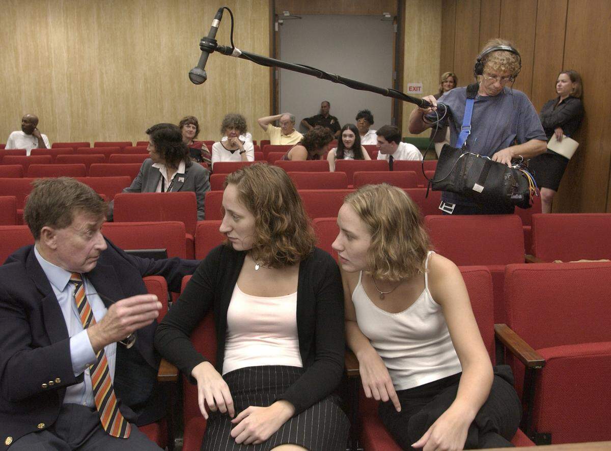 PETERSON3.NE.072203.CEL--DURHAM,NC--07/22/03--Michael Peterson (at left) speaks with his daughters Margaret (center) and Martha Ratliff during a break in his murder trial Tuesday as Yves Grasso holds a boom mike over their heads. Grasso is part of a documentary film crew following Peterson who is on trial for the murder of his wife Kathleen Peterson in December 2001 .STAFF PHOTO:CHUCK LIDDY