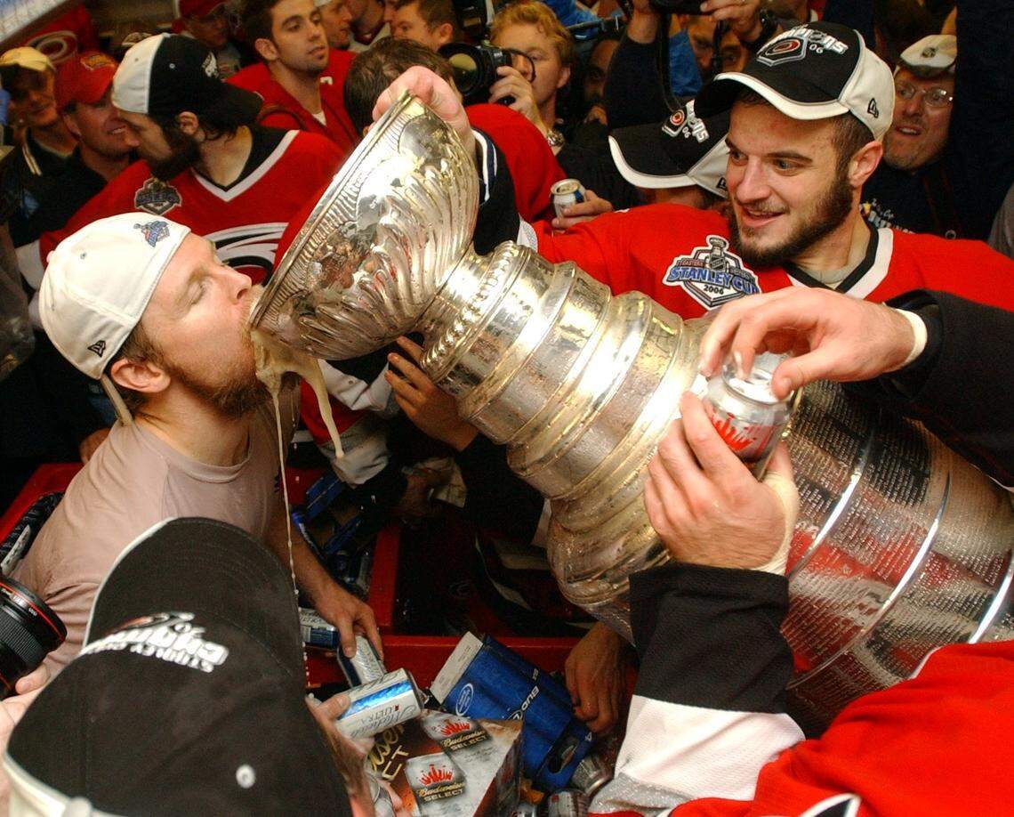 Carolina Hurricanes Kevyn Adams (left) drinks from the Stanley Cup in the locker room after beating the Edmonton Oilers 3-1 on June 19, 2006 during game 7 of the Stanley Cup Final.