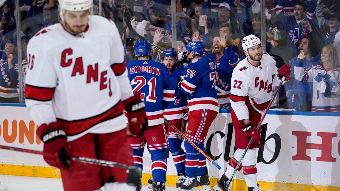 New York Rangers center Tyler Motte, center, celebrates with center Barclay Goodrow (21) and right wing Ryan Reaves (75) after scoring on Carolina Hurricanes goaltender Antti Raanta (32) during the first period of Game 6 of an NHL hockey Stanley Cup second-round playoff series, Saturday, May 28, 2022, in New York. (AP Photo/John Minchillo)