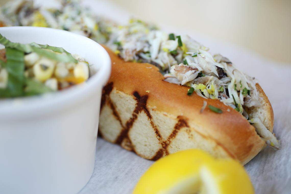 Locals Oyster Bar’s blue crab roll is simply dressed and heaped generously into a split top roll, it is served here with a side of local tomato and corn salad.