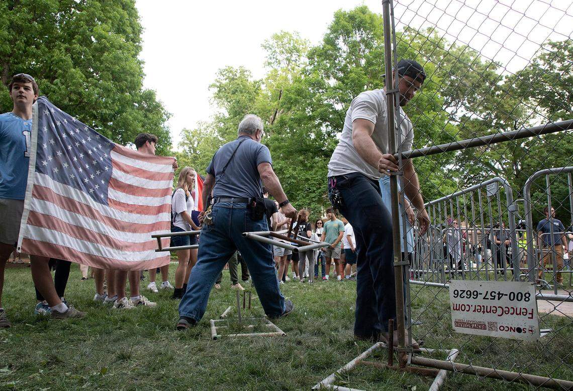 People watch as facilities services staff construct a fenced enclosure around a flagpole on the campus of UNC-Chapel Hill on Tuesday, April 30, 2024. UNC-Chapel Hill police charged 36 members of a pro-Palestinian “Gaza solidarity encampment” Tuesday morning after warning the group to remove its tents from campus or face possible arrest, suspension or expulsion from the university. Earlier in the afternoon, protesters took an American flag down from the flagpole and then mounted a Palestinian flag in its place.