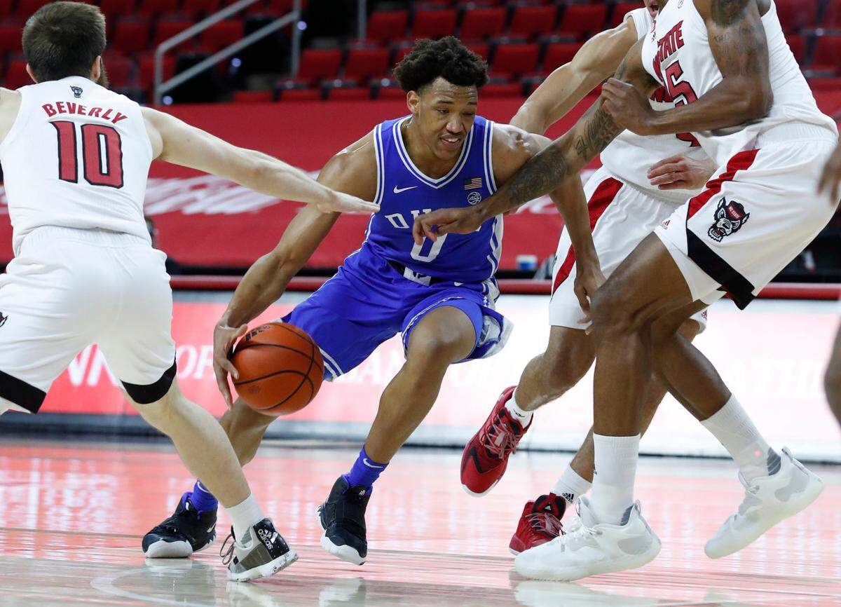 Duke’s Wendell Moore Jr. (0) drives around N.C. State’s Braxton Beverly (10) and Manny Bates (15) during the first half of N.C. State’s game against Duke at PNC Arena in Raleigh, N.C., Saturday, February 13, 2021.
