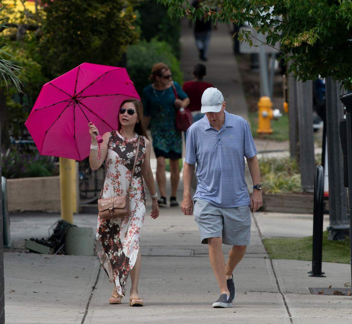 A couple walks down Glenwood Avenue in the Glenwood South district at 5pm Friday afternoon, July 21, 2023.