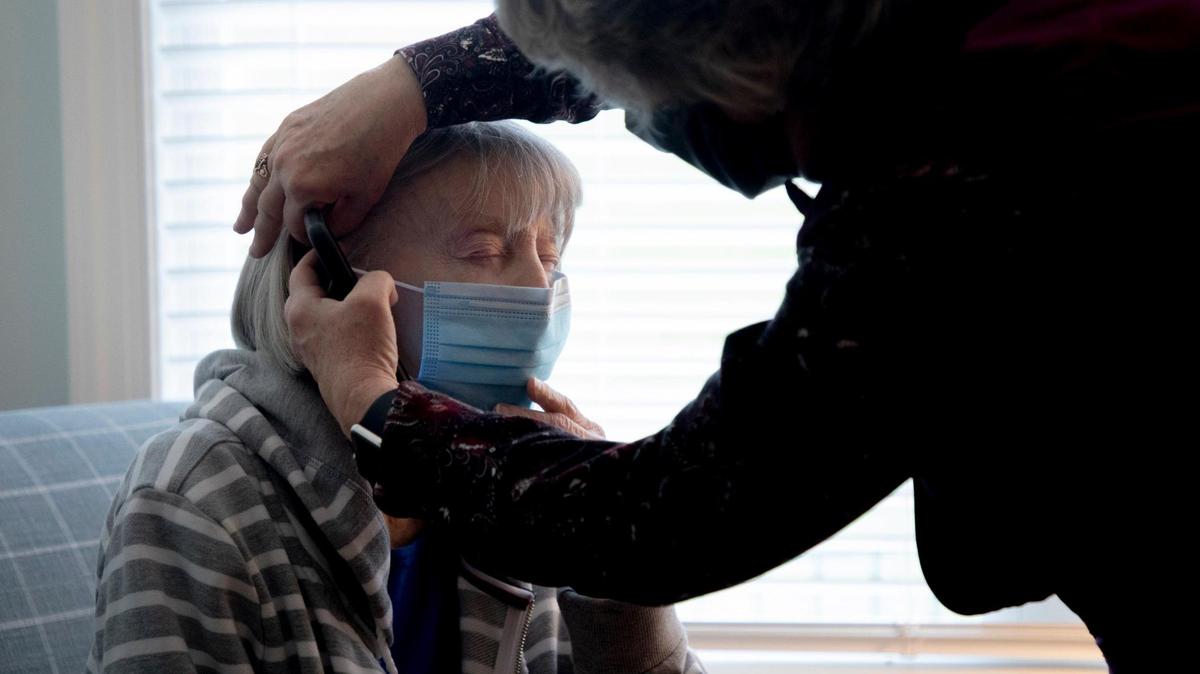 Thelma Miller puts on a mask with the help of her daughter, Cheryl Brown, during their visit in the new home care house on Thursday, Dec. 17, 2020, in Cary, N.C. Miller was one of the first of six residents to move into the home, with hopes of finding less isolation and more visitation freedom than traditional facilities can offer during the coronavirus pandemic