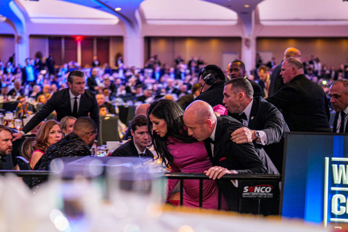 WASHINGTON, DC - APRIL 25: Secretary of War Pete Hegseth (L) stands as White House Deputy Chief of Staff for Policy Stephen Miller and his wife Katie Miller (C) are taken out of the ballroom by security agents during a shooting incident at the annual White House Correspondents Association Dinner at the Washington Hilton on April 25, 2026 in Washington, DC. According to reports, President Donald Trump, along with other government officials, were evacuated from the Washington Hilton gun shots.