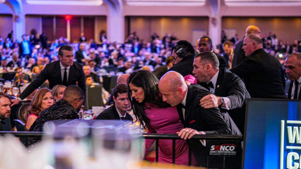 Secretary of War Pete Hegseth (L) stands as White House Deputy Chief of Staff for Policy Stephen Miller and his wife Katie Miller (C) are taken out of the ballroom by security agents during a shooting incident at the annual White House Correspondents Association Dinner at the Washington Hilton on April 25, 2026 in Washington.