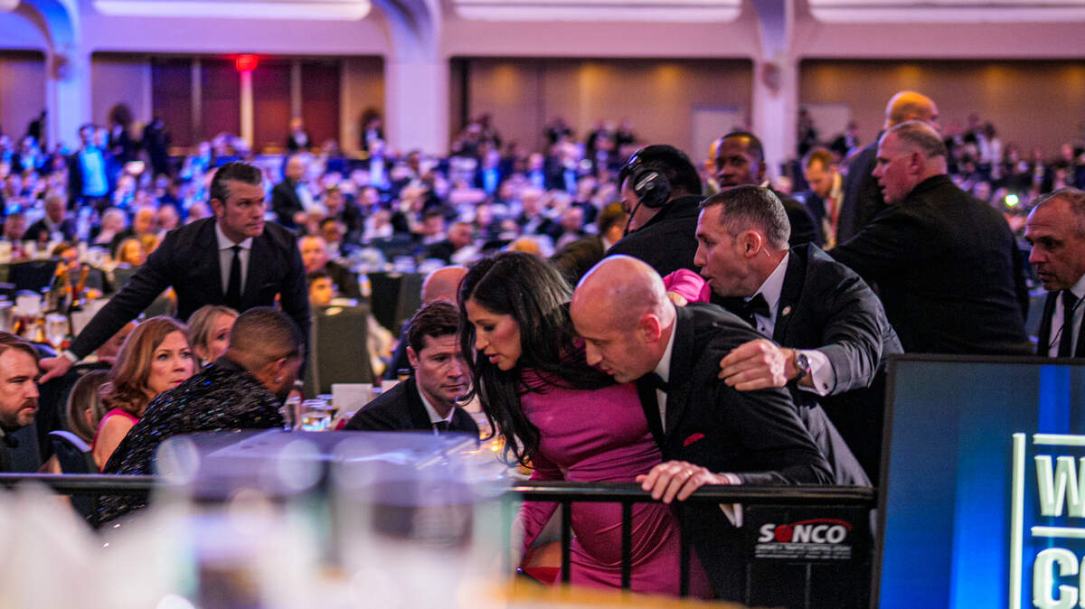 Secretary of War Pete Hegseth (L) stands as White House Deputy Chief of Staff for Policy Stephen Miller and his wife Katie Miller (C) are taken out of the ballroom by security agents during a shooting incident at the annual White House Correspondents Association Dinner at the Washington Hilton on April 25, 2026 in Washington.
