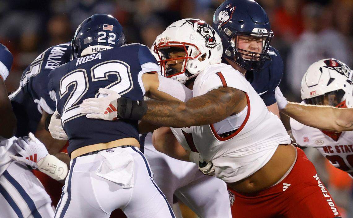 N.C. State defensive tackle Davin Vann (1) wraps up Connecticut running back Victor Rosa (22) during the first half of N.C. State’s game against UConn at Rentschler Field in East Hartford, Conn. Thursday, August 31, 2023.