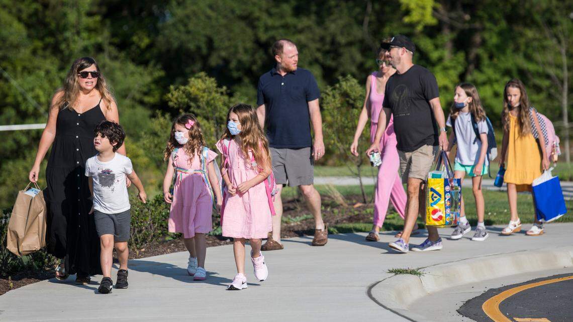 Parents walk their children towards Conn Elementary School in Raleigh, N.C. on the first day of school, Monday, Aug. 23, 2021.