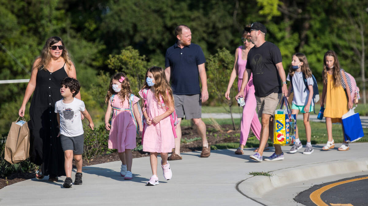 Parents walk their children towards Conn Elementary School in Raleigh, N.C. on the first day of school, Monday, Aug. 23, 2021.