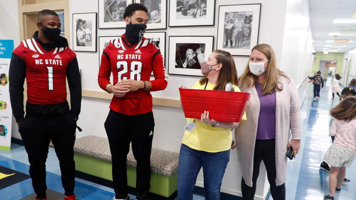 Hunter Magnet Elementary school first grade teacher Andrea Hough, center right, thanks N.C. State football players Isaiah Moore (1), Dylan Parham (28) and Trenton Gill (not in photo) after they delivered a gift basket to Hough in Raleigh, N.C. Friday, May 7, 2021. To the right is Hunter AIG coordinator Angie Parham, Dylan’s mother. To help celebrate teacher appreciation week, players from the Wolfpack football team surprised six teachers from five different schools with gift baskets filled with N.C. State goodies.