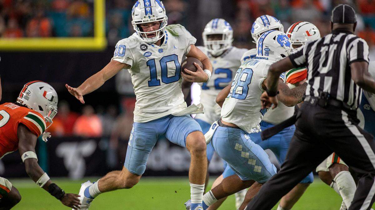 North Carolina quarterback Drake Maye (10) rushes for 11 yards in the fourth quarter ahead of Miami’s Te’Cory Couch (23) on Saturday, October 8, 2022 at Hard Rock Stadium in Miami Gardens, Florida. Maye rushed for 53 yards in the Tar Heels’ victory.
