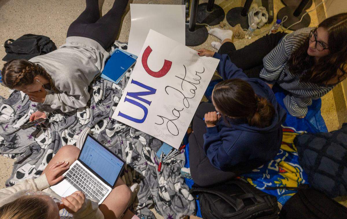 University of Kansas student Gabby Martinez works on a sign for the game, as he waits for her tickets to the Kansas vs. North Carolina basketball on Thursday, November 7, 2024 in Lawrence, Kansas.