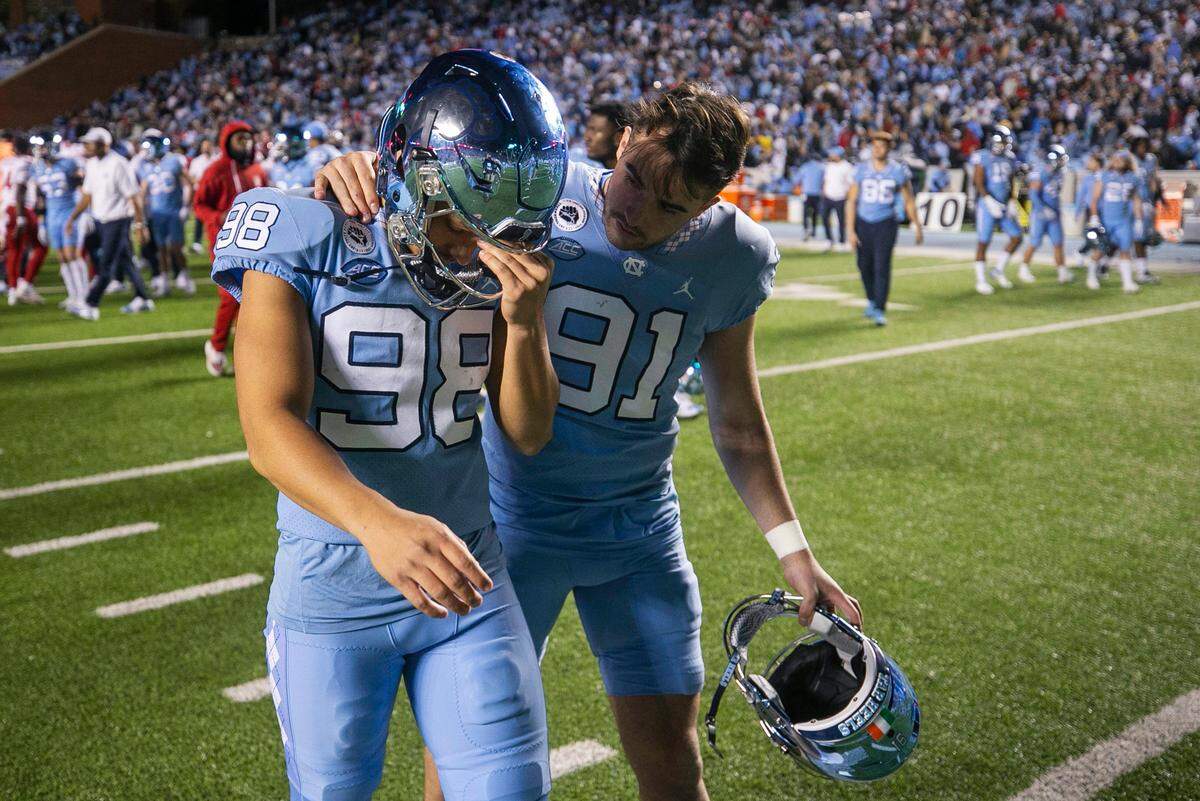 North Carolina punter Ben Kiernan (91) consoles kicker Noah Burnette (98) after Burnette missed a 35-yard field goal attempt in overtime to give N.C. State a 30-27 victory on Friday, November 25, 2022 at Kenan Stadium in Chapel Hill, N.C.