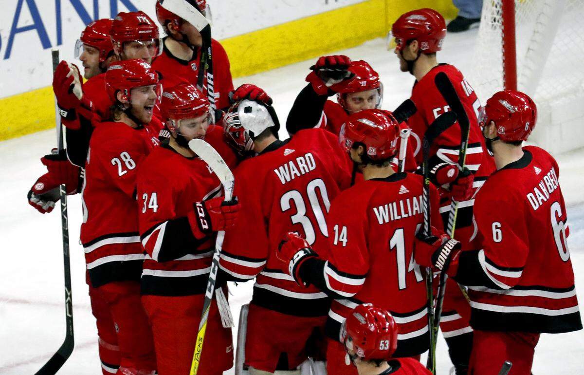 The Canes' Elias Lindholm (28) celebrates his winning goal with goaltender Cam Ward (30) and other teammates at the end of the game.