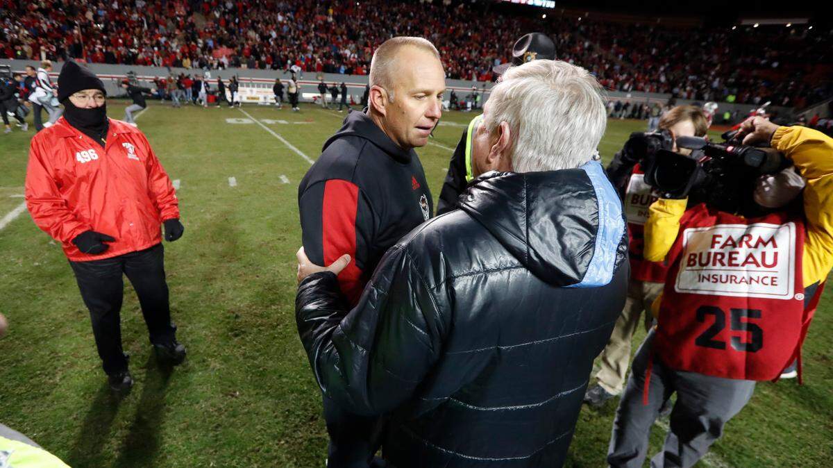 N.C. State head coach Dave Doeren greets North Carolina head coach Mack Brown after N.C. State’s 34-30 victory over UNC at Carter-Finley Stadium in Raleigh, N.C., Friday, November 26, 2021.
