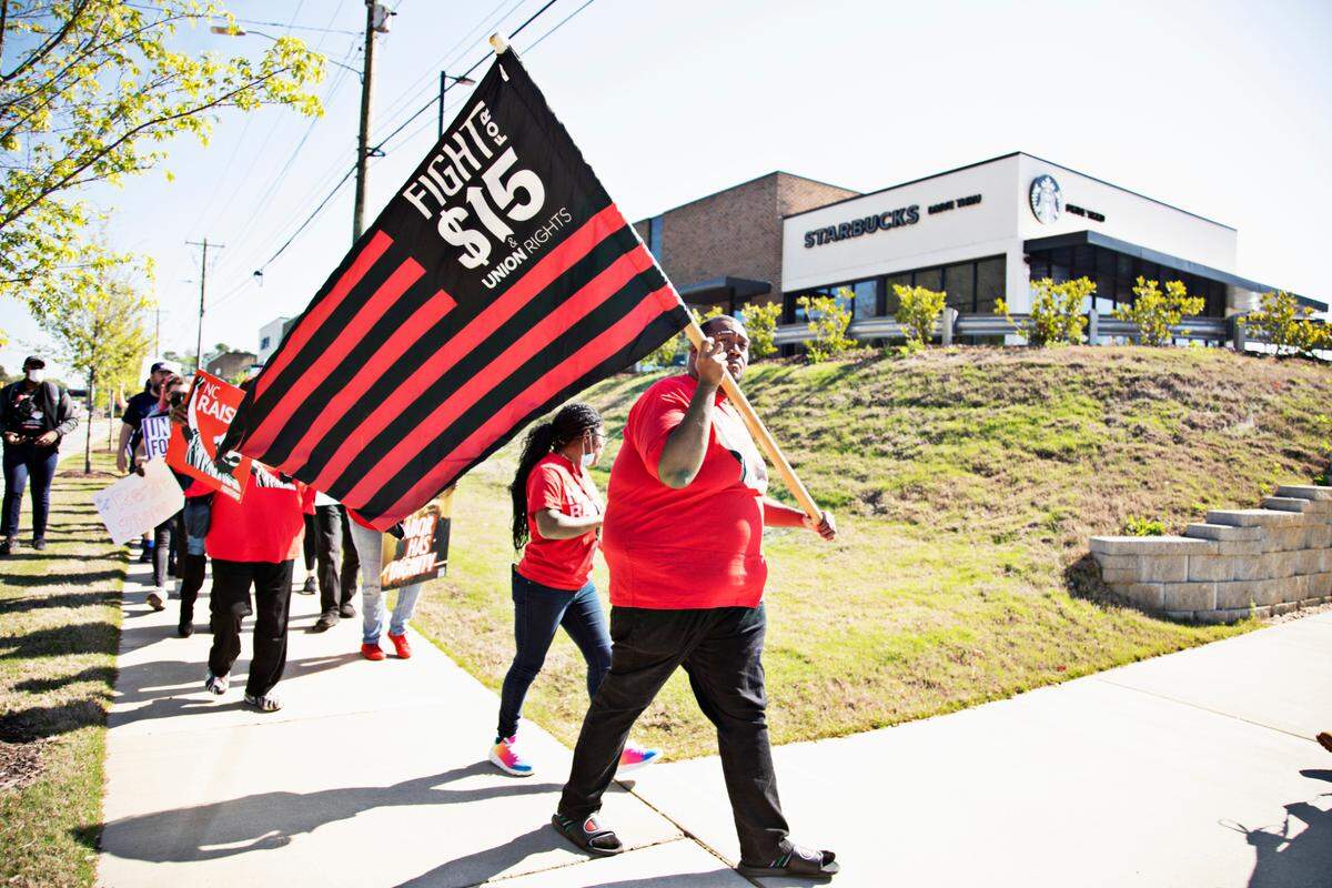 Protestors including Earl Bradley with Fight for $15, right, march outside of the Wake Forest & Six Forks Starbucks in Raleigh on April 11, 2022, in response to the firing of vocal union leader Sharon Gilman earlier this month.