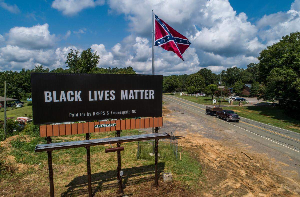 A Black Lives Matter billboard stands next to Confederate flag on US Highway 64 in Pittsboro Thursday, July 16, 2020. An online fundraiser helped pay for the billboard near where a controversial Confederate statue was removed last year.
