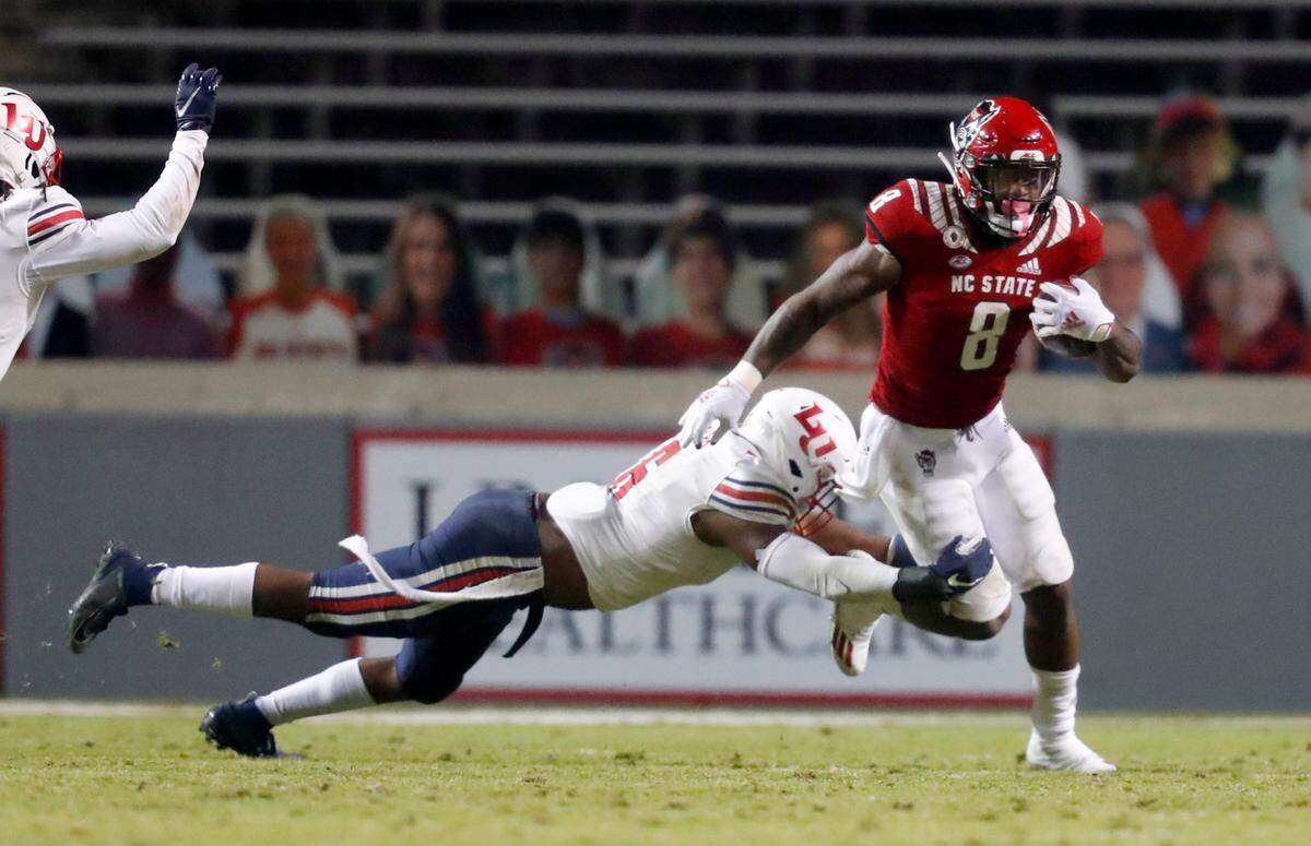 N.C. State running back Ricky Person Jr. (8) tries to escape the tackle by Liberty linebacker Anthony Butler (6) during the second half of N.C. State’s 15-14 victory over Liberty at Carter-Finley Stadium in Raleigh, N.C., Saturday, Nov. 21, 2020.