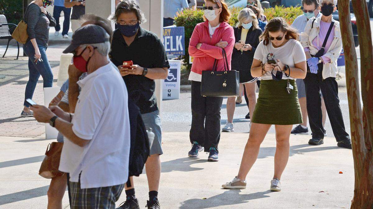 Voters stand in line outside 4525 Sharon Road waiting to cast their ballots in Charlotte on the first day of voting on Thursday, October 15, 2020.
