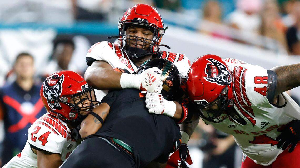N.C. State defensive end Savion Jackson (90) wraps up Miami running back Jaylan Knighton (4) as Derrek Pitts Jr. (24) and Cory Durden (48) come in to help with the tackle during the first half of N.C. Stateís game against Miami at Hard Rock Stadium in Miami Gardens, Fla. Saturday, Oct. 23, 2021.