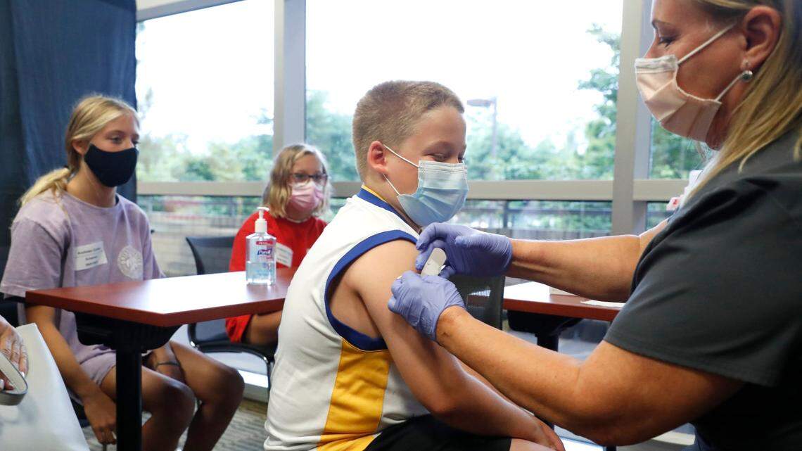 Eli Strickland, 12, gets a band aid after getting his first COVID-19 vaccine shot from Pam Scott, RN, during the WakeMed Back-to-School Blitz vaccine clinic at the WakeMed Raleigh Campus in Raleigh, N.C., Sunday, August 1, 2021. Elis sisters, they are triplets, Campbell, left, and Emma, watch.