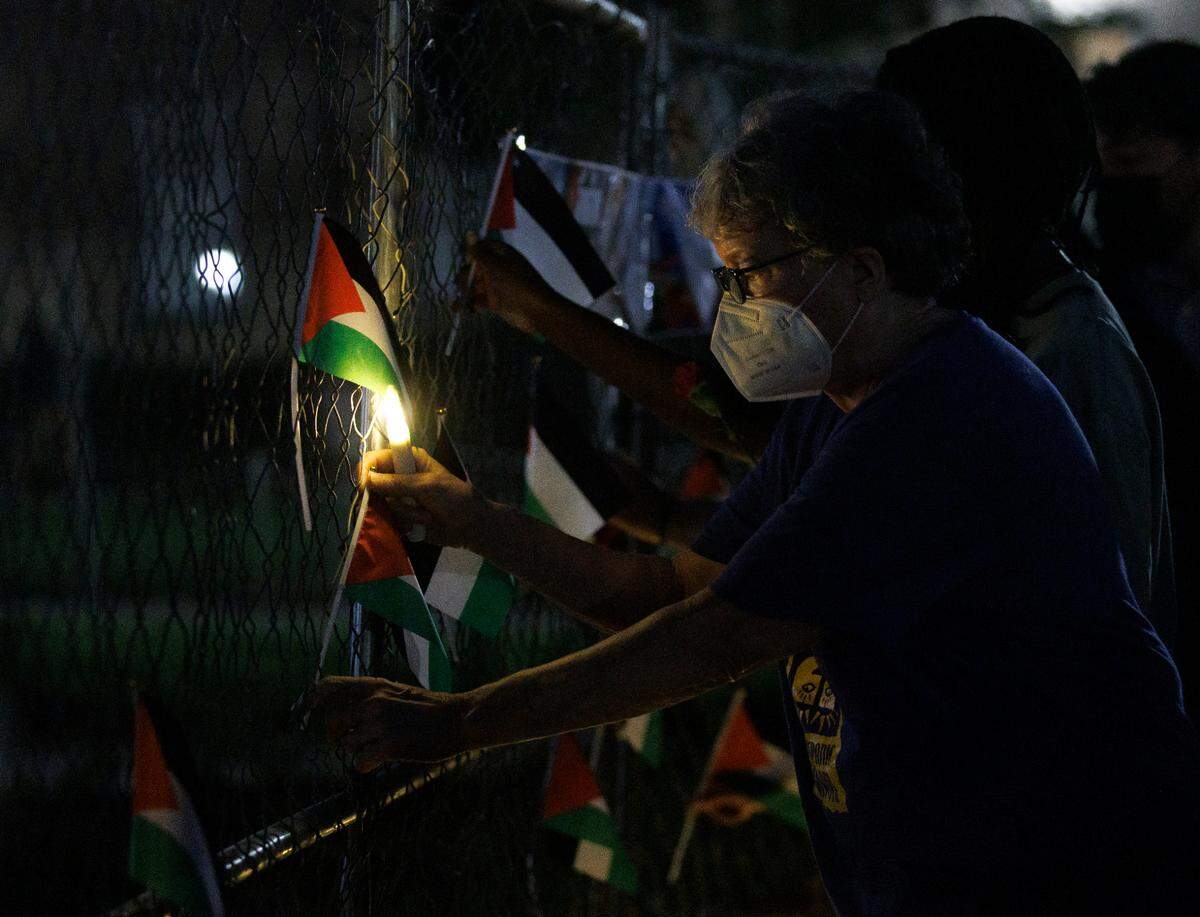 A person places a Palestinian flag at a memorial near the Old Well at the conclusion of a vigil held by the UNC chapter of Students for Justice in Palestine on Monday, Oct. 7, 2024, in Chapel Hill, N.C. The vigil was intended to honor those who have been killed during Israel’s counter-campaign against Hamas in the past year.
