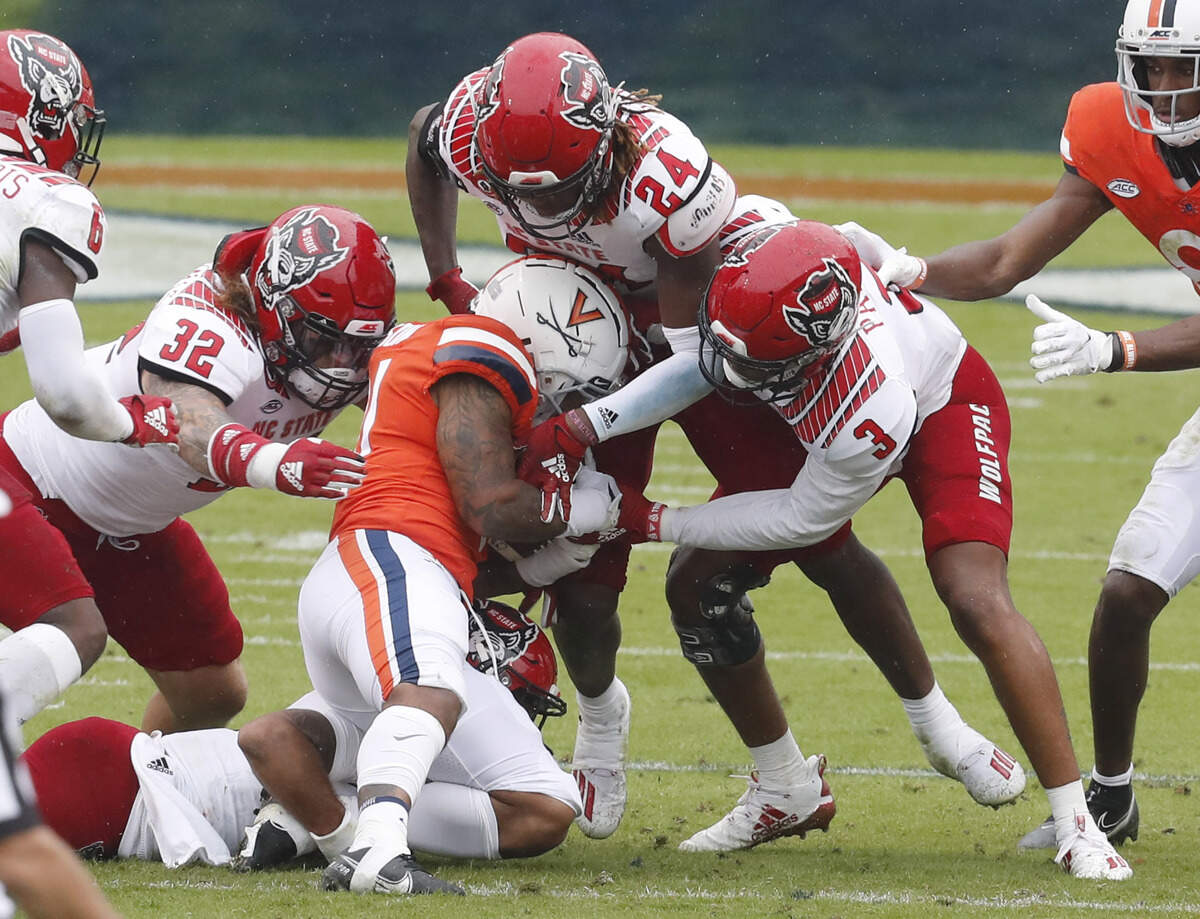 N.C. State’s Tanner Ingle (10), bottom, with Drake Thomas (32), Malik Dunlap (24) and Taiyon Palmer (3) tackle Virginia running back Shane Simpson (31) during the first half of N.C. State’s game against Virginia at Scott Stadium in Charlottesville, Va., Saturday, Oct. 10, 2020.