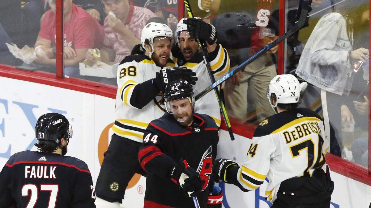 Boston’s Brad Marchand (63) celebrates with David Pastrnak (88) as Carolina’s Calvin de Haan (44) skates away after Pastrnak scored during the second period of the Carolina Hurricanes’ game against the Boston Bruins in game four of the Eastern Conference finals at PNC Arena in Raleigh, N.C. Thursday, May 16, 2019. Boston’s Jake DeBrusk (74) skates in.