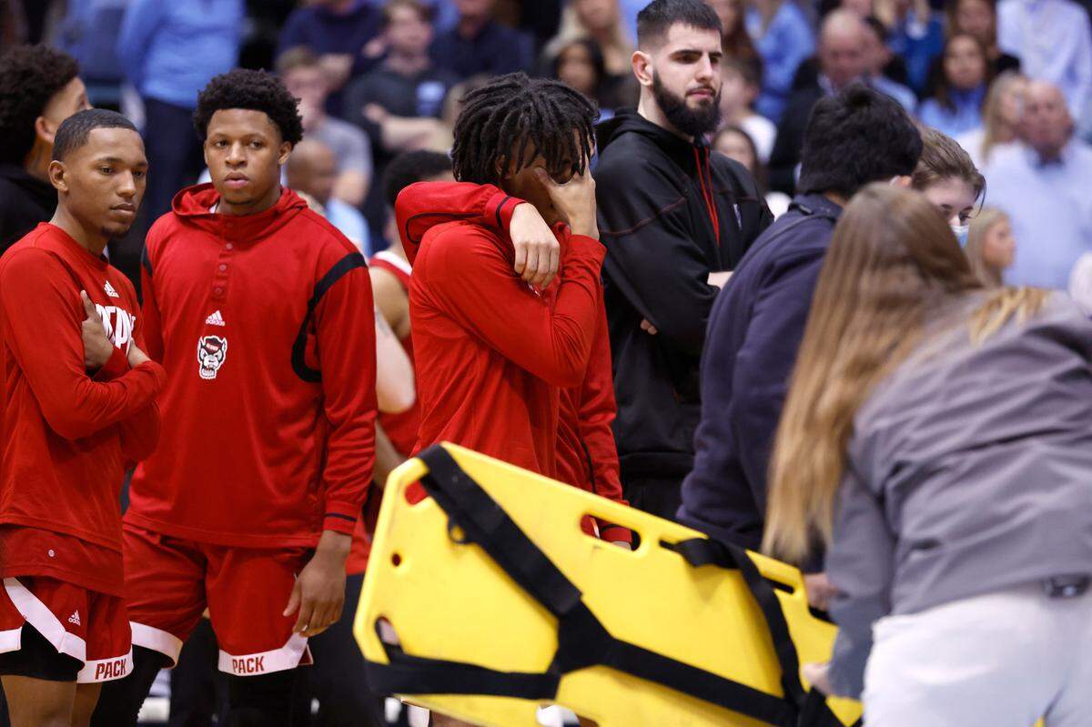 Players including N.C. State’s Breon Pass react as N.C. State’s Terquavion Smith is looked at after being injured during the second half of N.C. State’s game against UNC at the Smith Center in Chapel Hill, N.C., Saturday, Jan. 21, 2023.