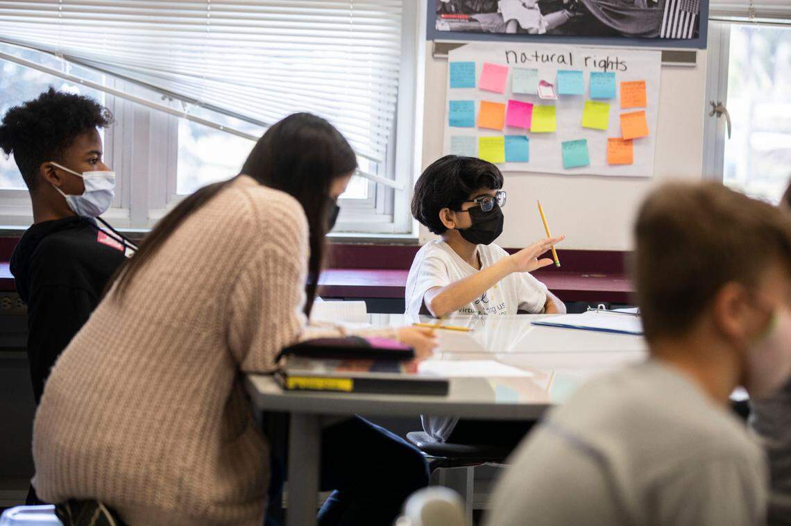 From left, McDougle Middle School 7th grade students Tyshaun Pope, 13, Valerie Dones, 13, and Anika Kurup, 13, listen to their social studies teacher during a lesson on African history in Chapel Hill, N.C. on Friday, Feb. 18, 2022.