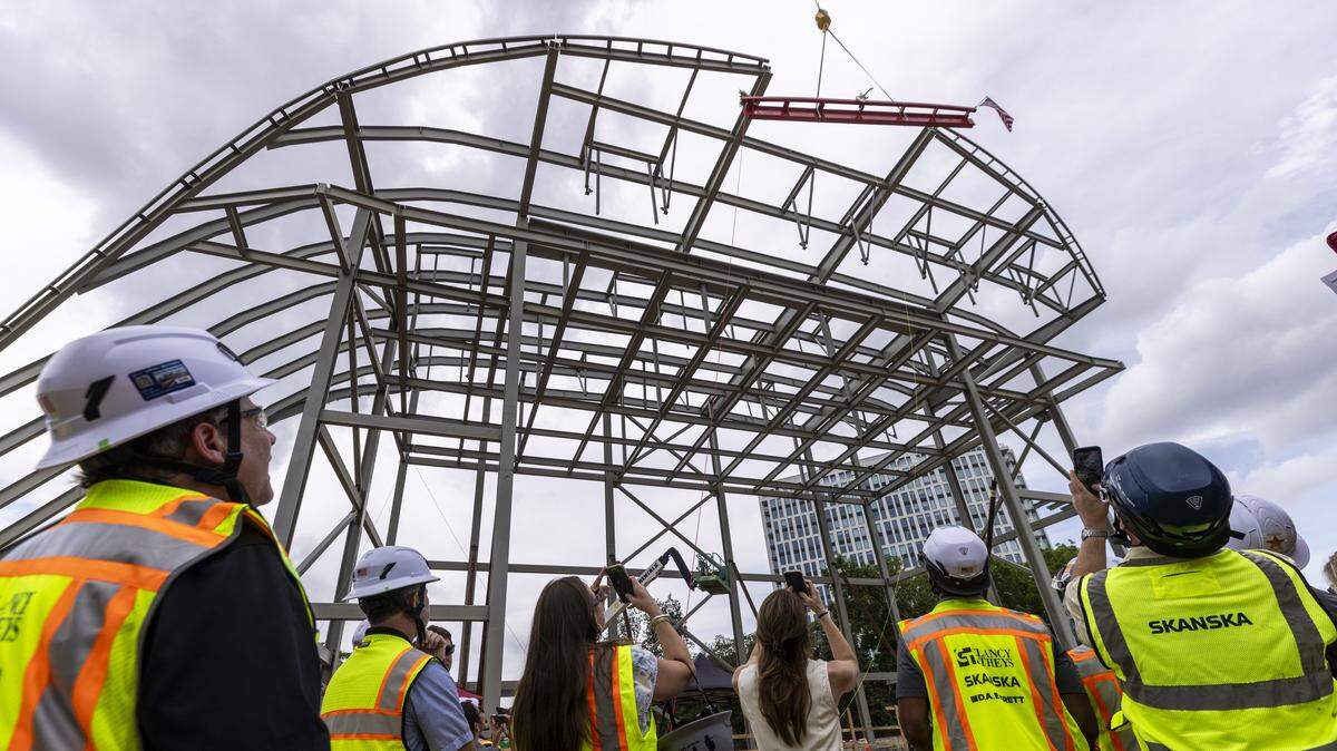 Onlookers watch as a steel beam is hoisted into place during a topping-out ceremony at the new Red Hat Amphitheater in downtown Raleigh on Tuesday, May 26, 2026. The new amphitheater is expected to open in spring 2027.