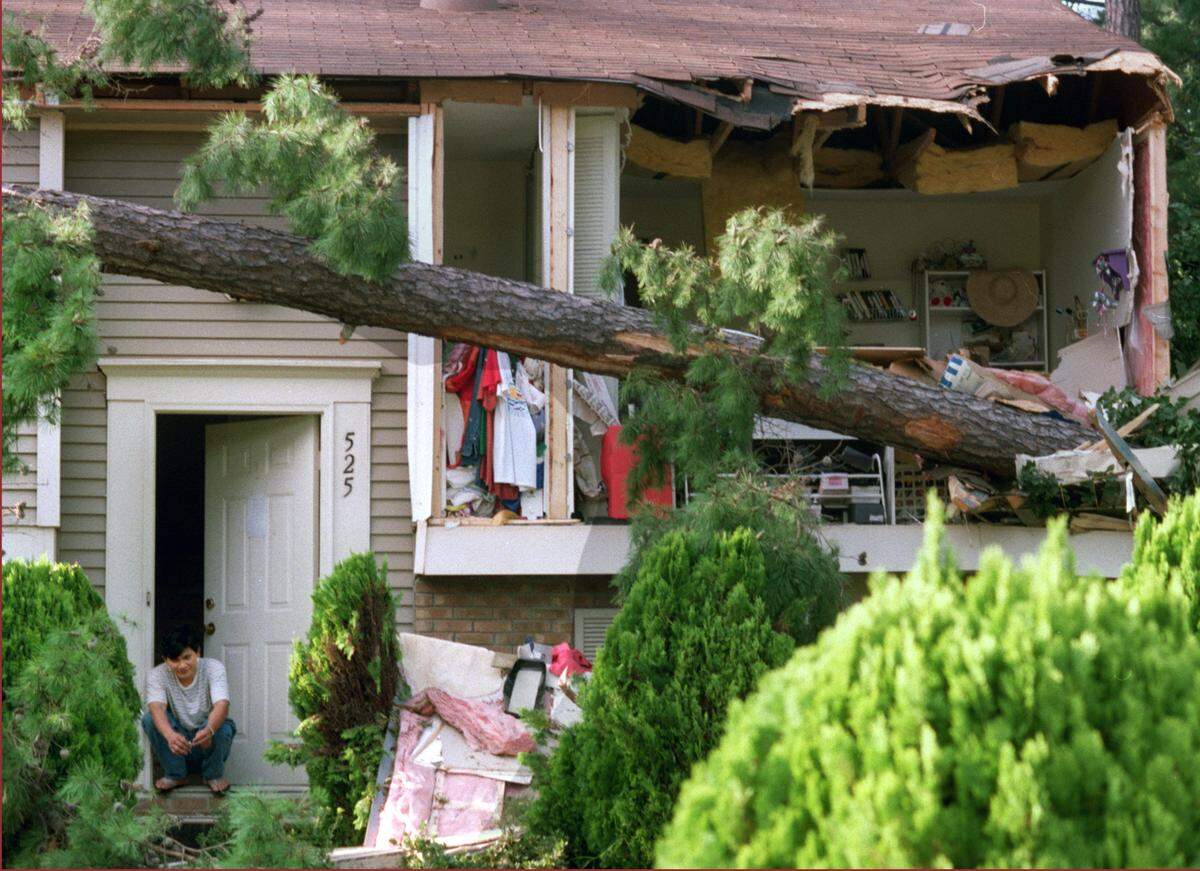 Joshua Nguyen sits in the doorway of his uncle’s Tuan Do’s home as he waits for him to come home to his wrecked house on Drolmond Rd. in North Raleigh. The tree tore off the front of the house during Hurricane Fran.