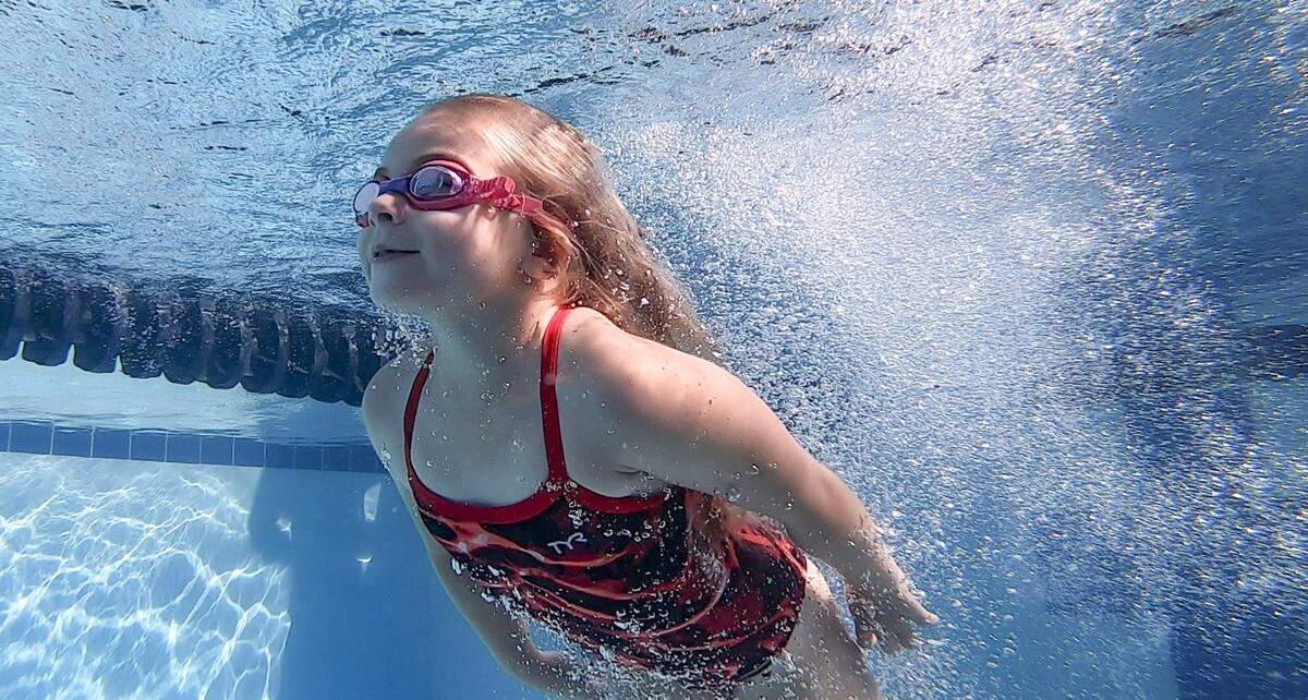 Gracie Kenjarski swims to the surface after practicing her dives during practice at Cary Park Swim Club on July 2, 2024.