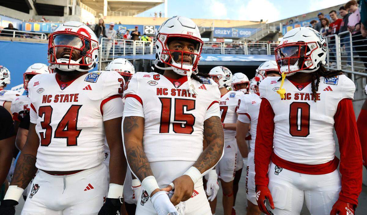From left, N.C. State’s Delbert Mimms III (34), Keyon Lesane (15) and Sean Brown (0) get ready to run out onto the field to warm up before N.C. State’s game against Kansas State in the Pop-Tarts Bowl at Camping World Stadium in Orlando, Fla., Thursday, Dec. 28, 2023.