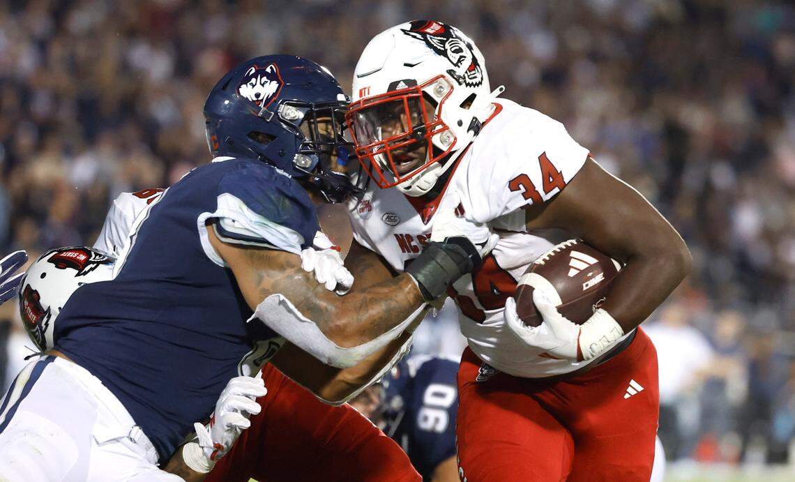 N.C. State running back Delbert Mimms III (34) pushes off Connecticut linebacker Jackson Mitchell (8) to score on a one-yard touchdown run during the second half of N.C. State’s 24-14 victory over UConn at Rentschler Field in East Hartford, Conn. Thursday, August 31, 2023.