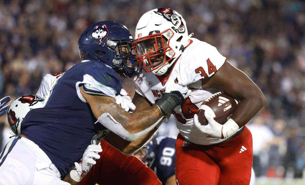 N.C. State running back Delbert Mimms III (34) pushes off Connecticut linebacker Jackson Mitchell (8) to score on a one-yard touchdown run during the second half of N.C. State’s 24-14 victory over UConn at Rentschler Field in East Hartford, Conn. Thursday, August 31, 2023.