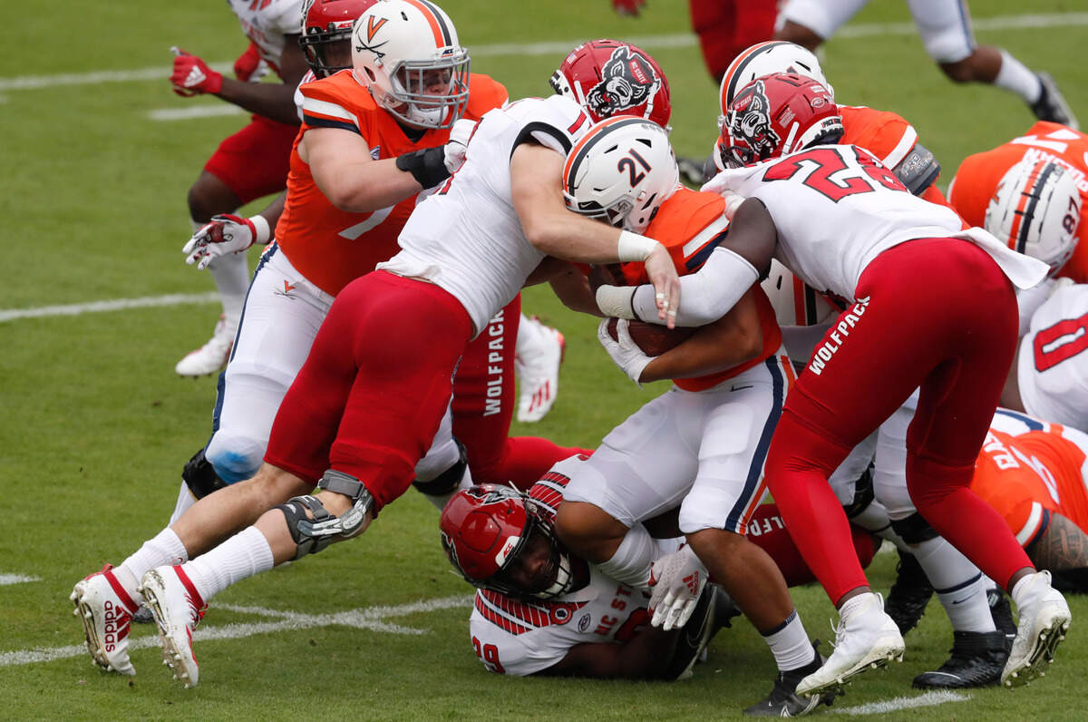 N.C. State’s Payton Wilson (11), Ibrahim Kante (28) and Alim McNeill (29) combine to bring down Virginia running back Wayne Taulapapa (21) during the first half of N.C. State’s game against Virginia at Scott Stadium in Charlottesville, Va., Saturday, Oct. 10, 2020.