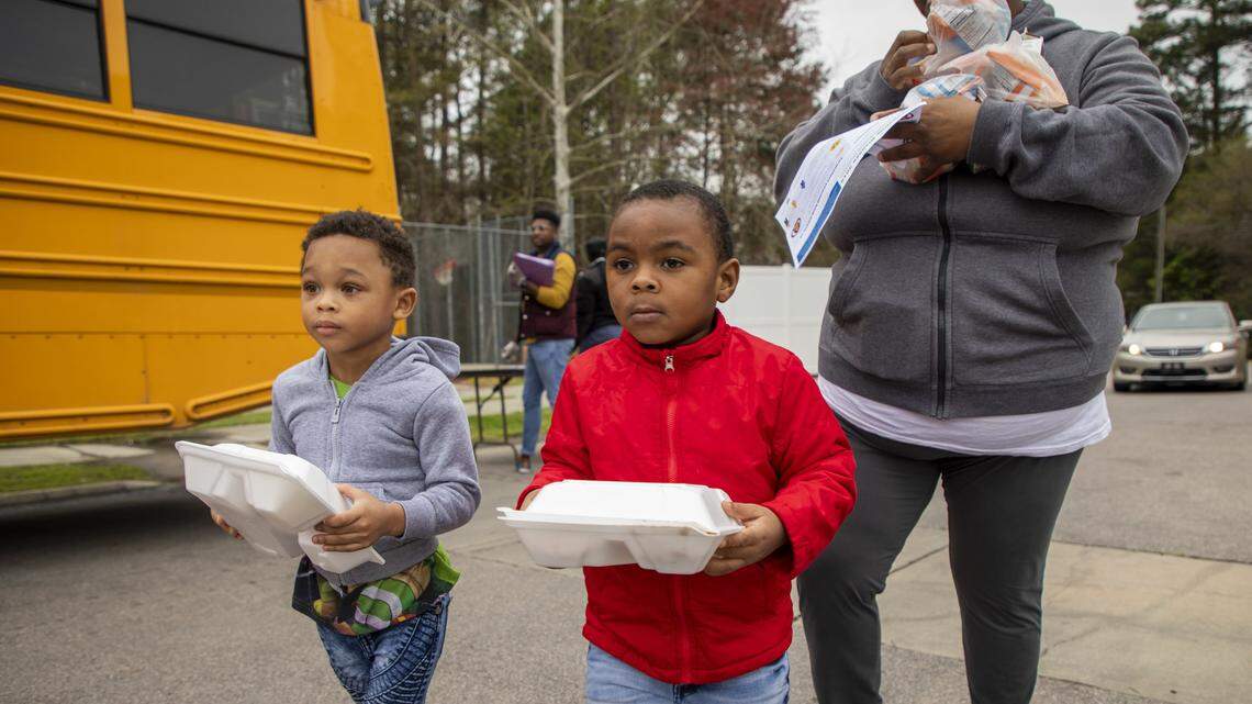 Nazir Williams, 3, left, and J-Sheer Williams, 3, walk home with their mother Saleemah Williams and their lunch provided at one of about 67 meal distribution sites for Durham Public Schools students after all North Carolina public schools closed in an effort to slow the spread of the coronavirus. Photographed March 26, 2020, in Durham, N.C.