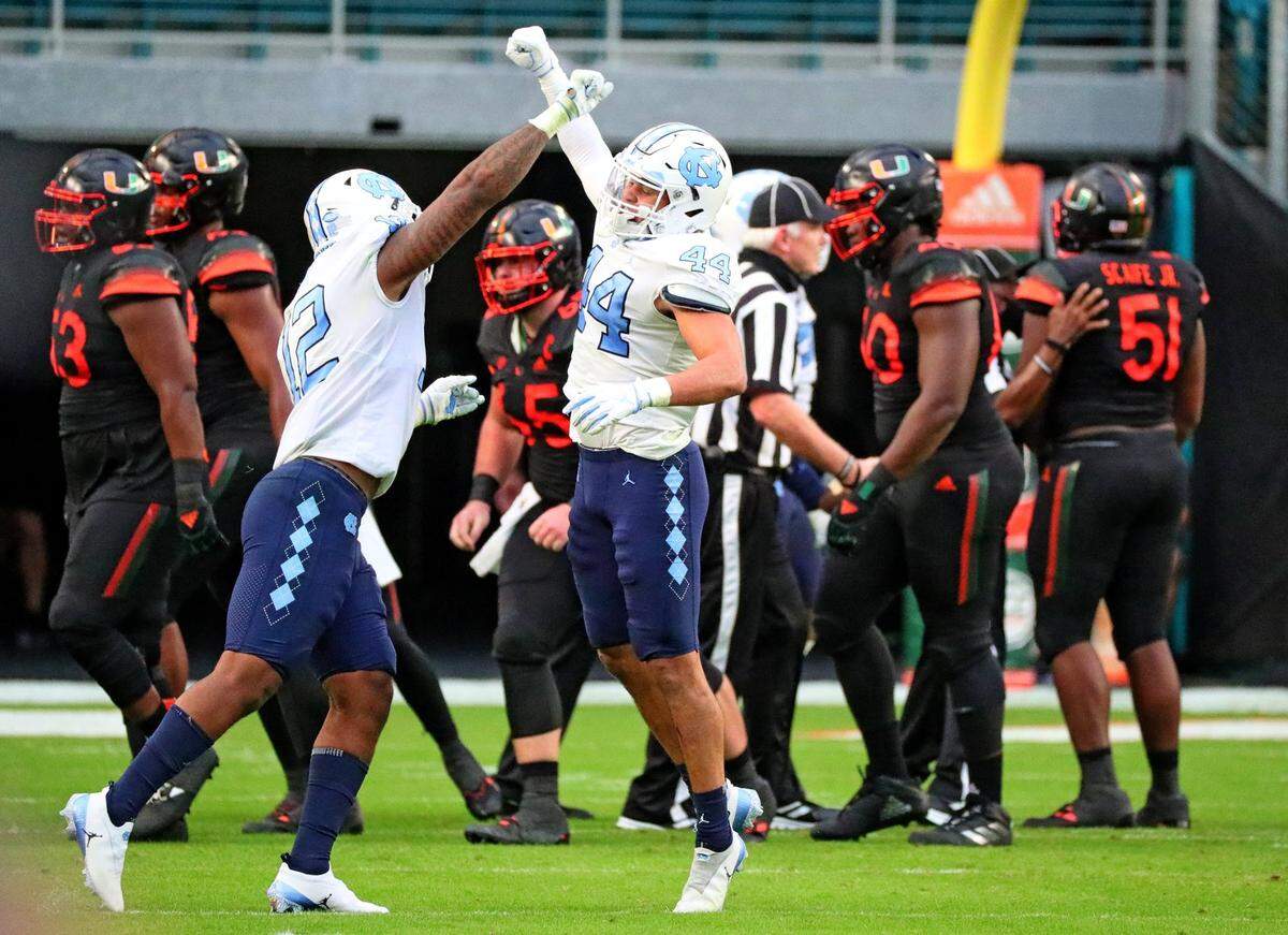 North Carolina Tar Heels linebackers Tomon Fox (12) and Jeremiah Gemmel (44) celebrate a stop in the second quarter at Hard Rock Stadium In Miami Gardens, Florida, Saturday, December 12, 2020.