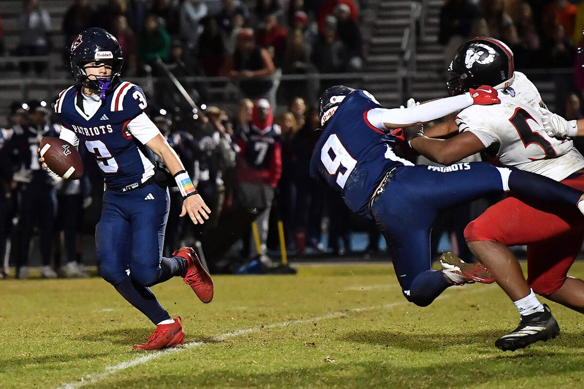 Apex Friendship quarterback Ethan McGarrigan (3)  scrambles to get away from Rolesville's Malachi Harris (54) during overtime. The Apex Friendship Patriots and the Rolesville Rams met in  the second round of the  NCHSAA 8A Playoff game in Apex, N.C. on November 14, 2025. Rolesville wins 14-7 in overtime.