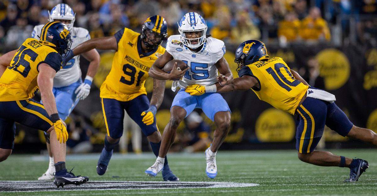 North Carolina quarterback Conner Harrell (15) looks for running room on a 15-yard carry in the first quarter against West Virginia’s Jared Bartlett (10) on Wednesday, December 27, 2023 at Bank of American Stadium in Charlotte, N.C.
