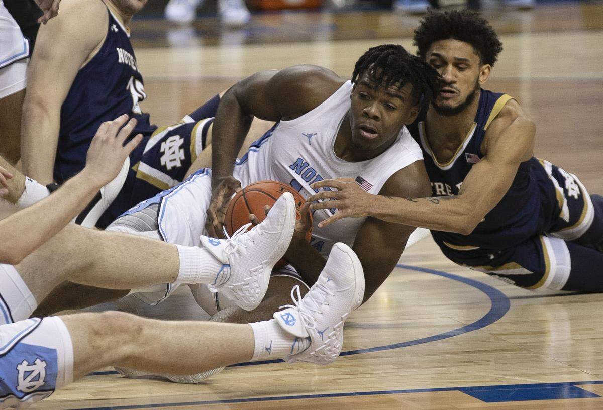 North Carolina’s Day’Ron Sharpe (11) hits the court in a battle for a loose ball with Notre Dame’s Prentiss Hubb (3) during the first half on Wednesday, March 10, 2021 during the ACC Tournament at the Greensboro Coliseum in Greensboro, N.C.