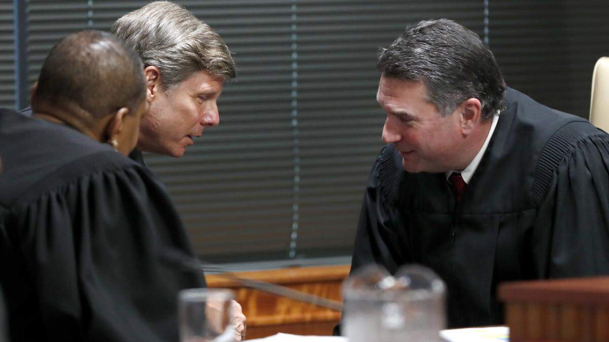 Judges Alma Hinton, left, Paul Ridgeway and Joseph Crosswhite confer during the first day of the gerrymandering trial challenging the North Carolina legislature district lines Monday, July 15, 2019.