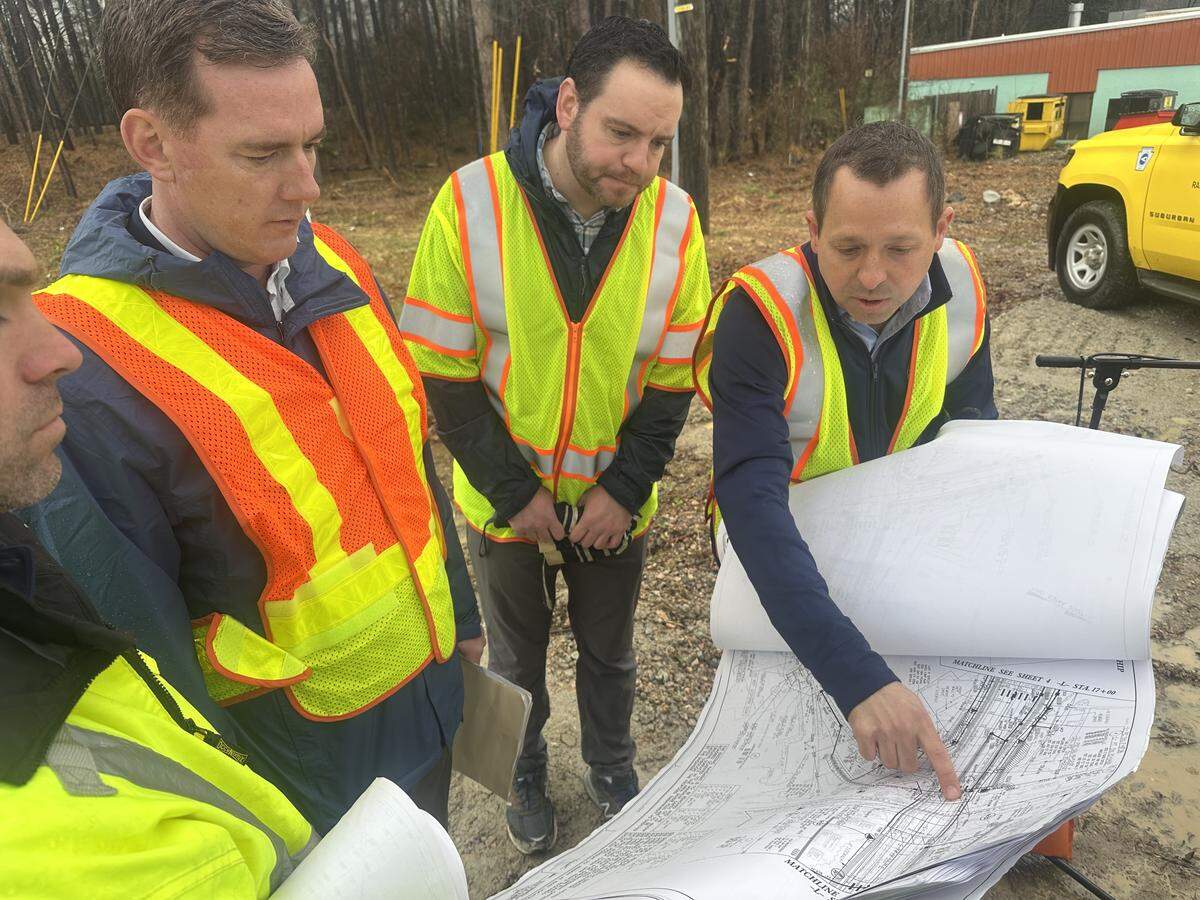 Jason Orthner, director of the N.C. Department of Transportation’s Rail Division, explains plans for a new bridge to Drew Feeley of the Federal Railroad Administration, center, and state Transportation Secretary Daniel Johnson, left, on Feb. 26, 2026. The bridge, now under construction, will carry New Hope Church Road over a railroad line in North Raleigh.